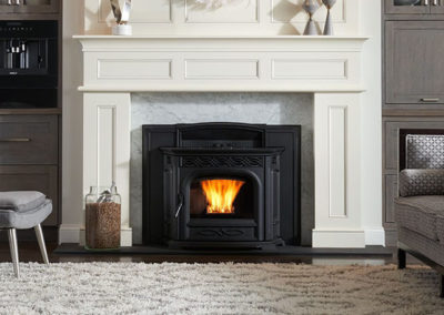 Black iron stove under a large white mantel